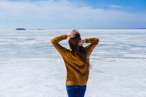 Anonymous female standing near frozen sea on ice surface