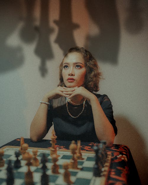 Woman Sitting in Front of Chess Board