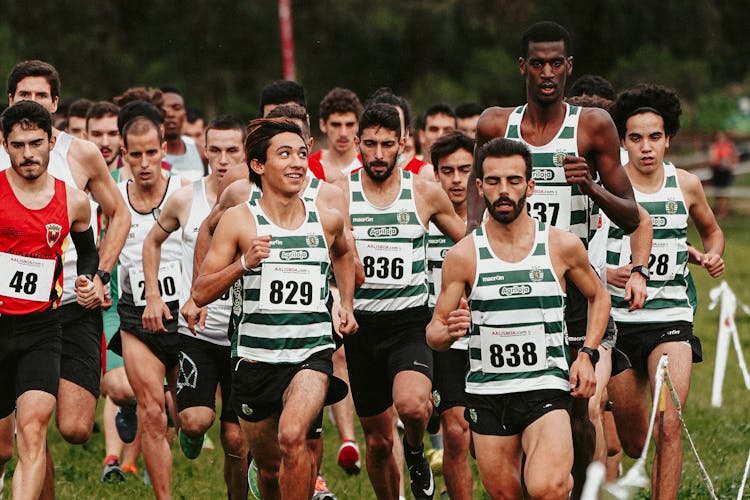 Group Of Men Running On A Grassy Field