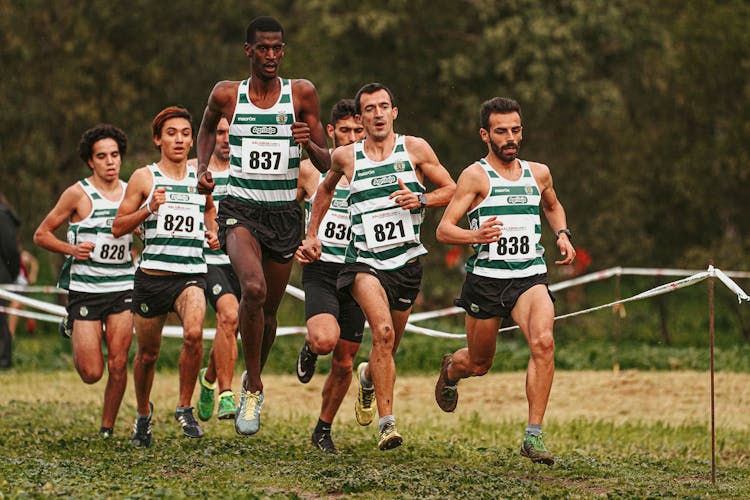 Group Of Men Running On A Grassy Field