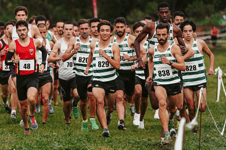 Group Of Men Running On A Grassy Field