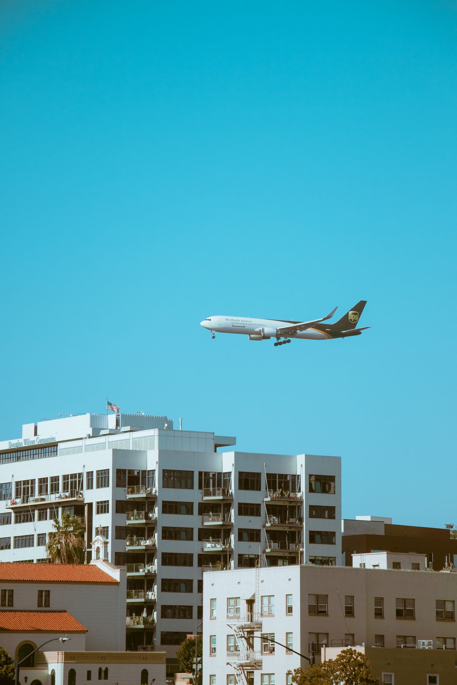Commercial airplane flying over San Diego, California under clear blue skies