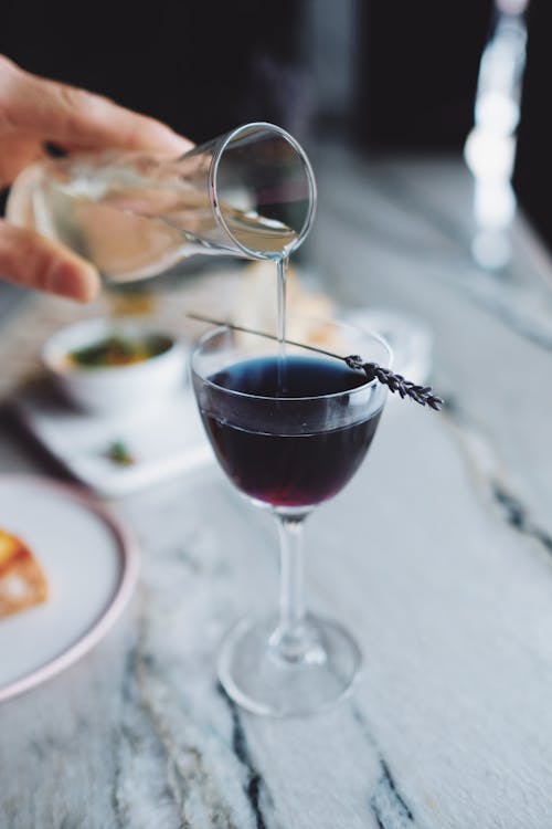 Close-Up Shot of a Person Pouring Wine on a Glass