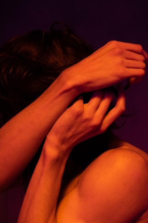 Free Artistic expression through a dramatic nude portrait bathed in warm neon lighting. Stock Photo