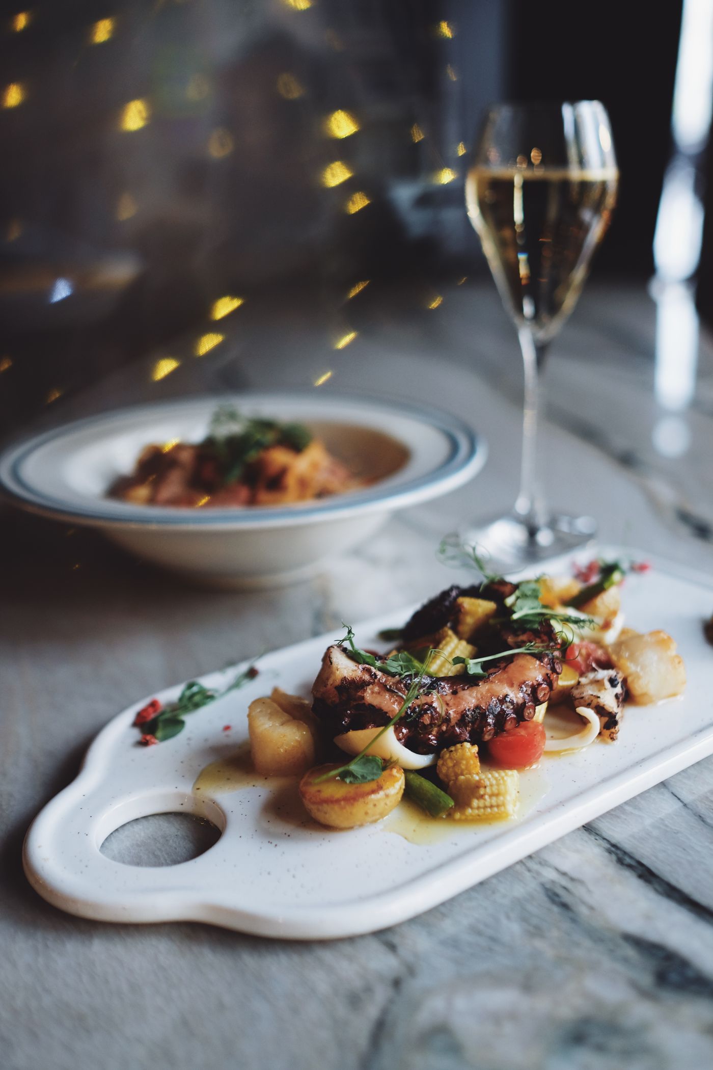 Grilled seafood plate served with a chilled glass of sparkling wine at a restaurant table