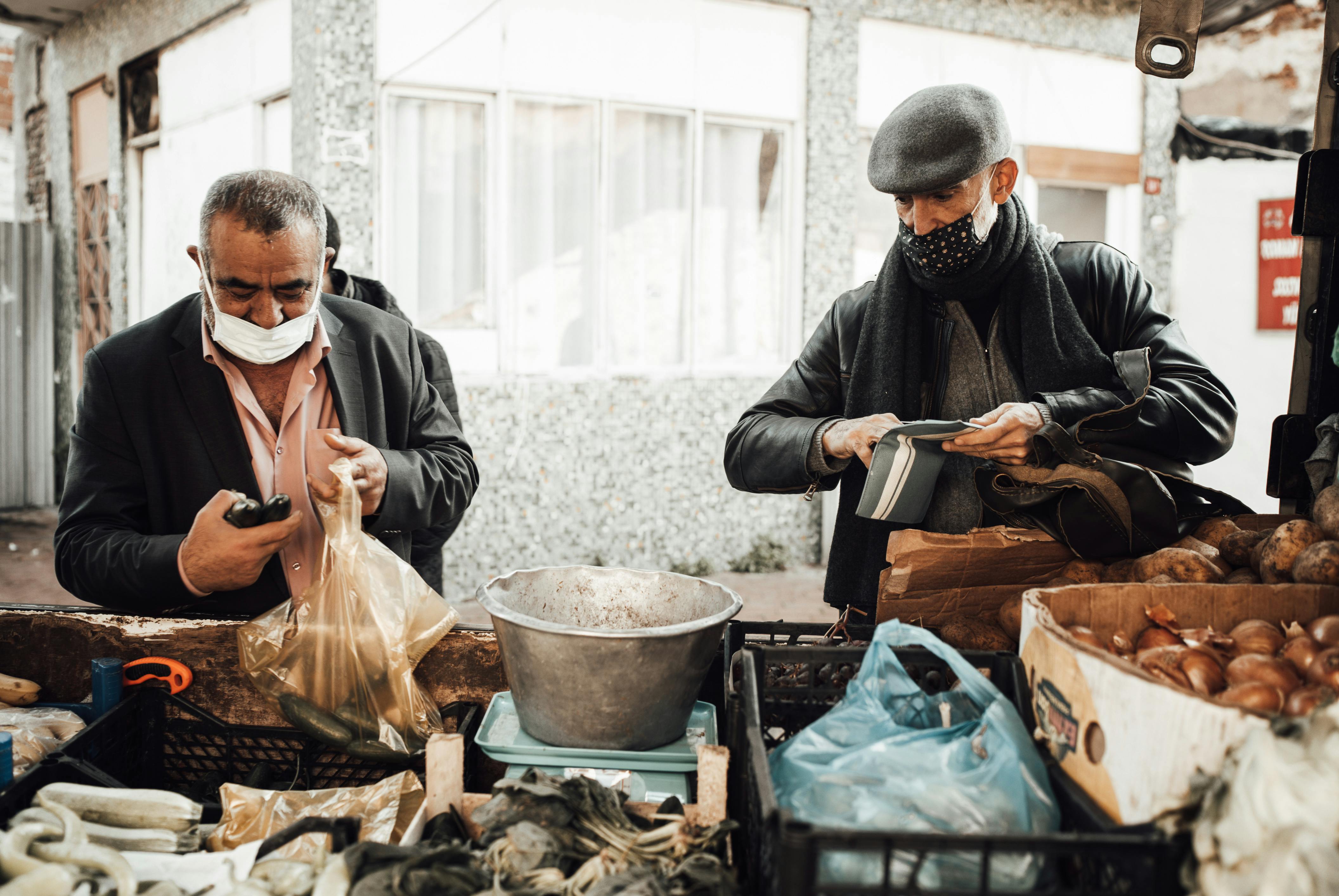 multiethnic men in masks on market near stall with products