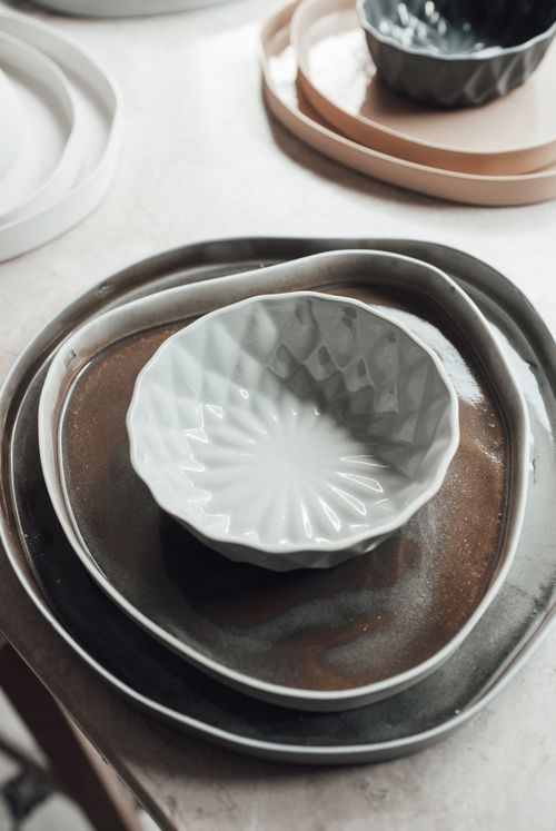 Free Different uneven bowls with geometric ornament in plates on white surface in light workshop Stock Photo