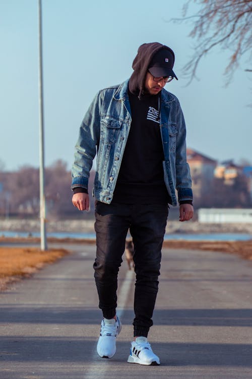A Man in Denim Jacket Standing on the Road