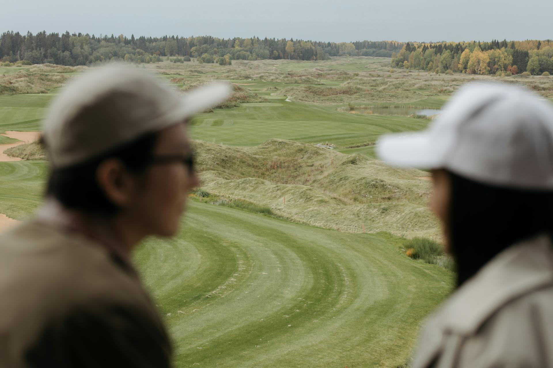 A couple enjoys a peaceful view of a lush golf course surrounded by trees.