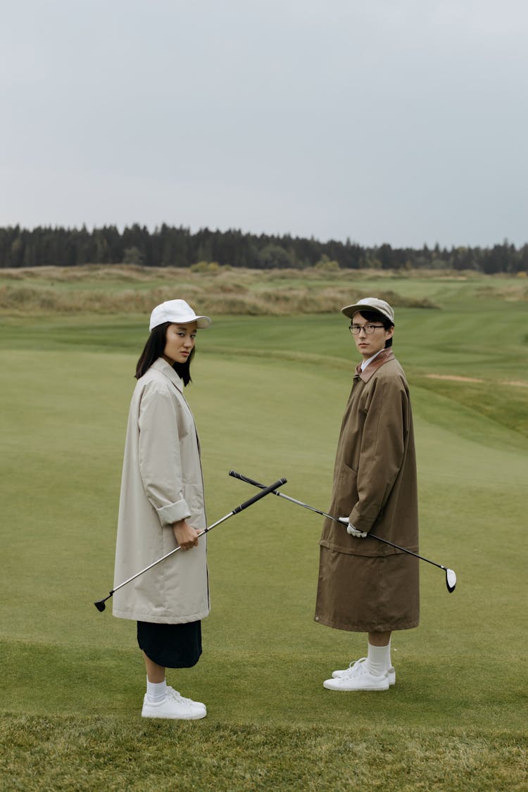 Stylish Couple Holding Golf Clubs 