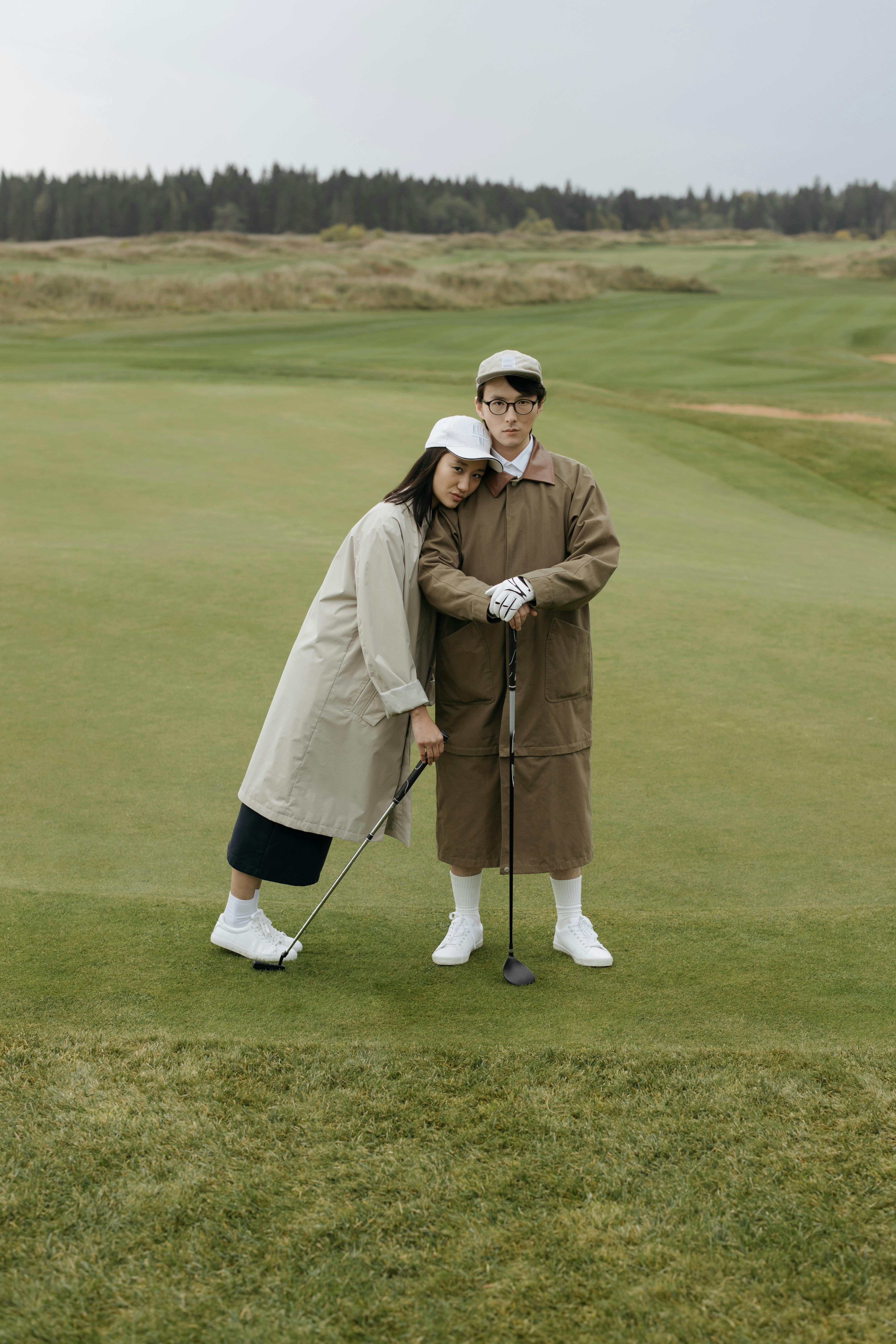 couple on a grassfield holding gold clubs