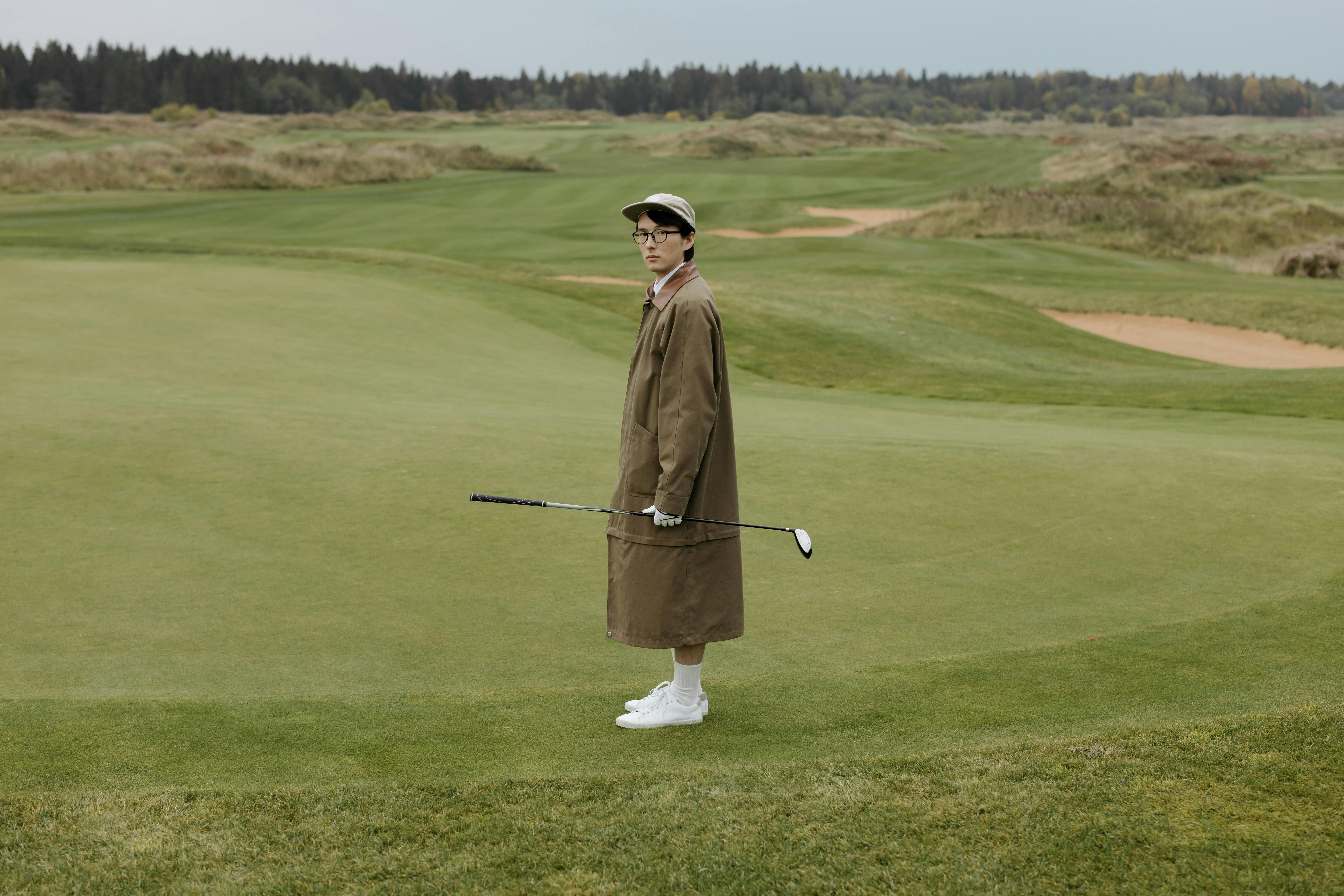 Man in Brown Robe Holding Golf Club on Green Grass Field \u00b7 Free Stock Photo