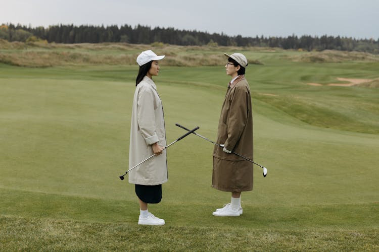 Two People Standing On Golf Course Face To Face