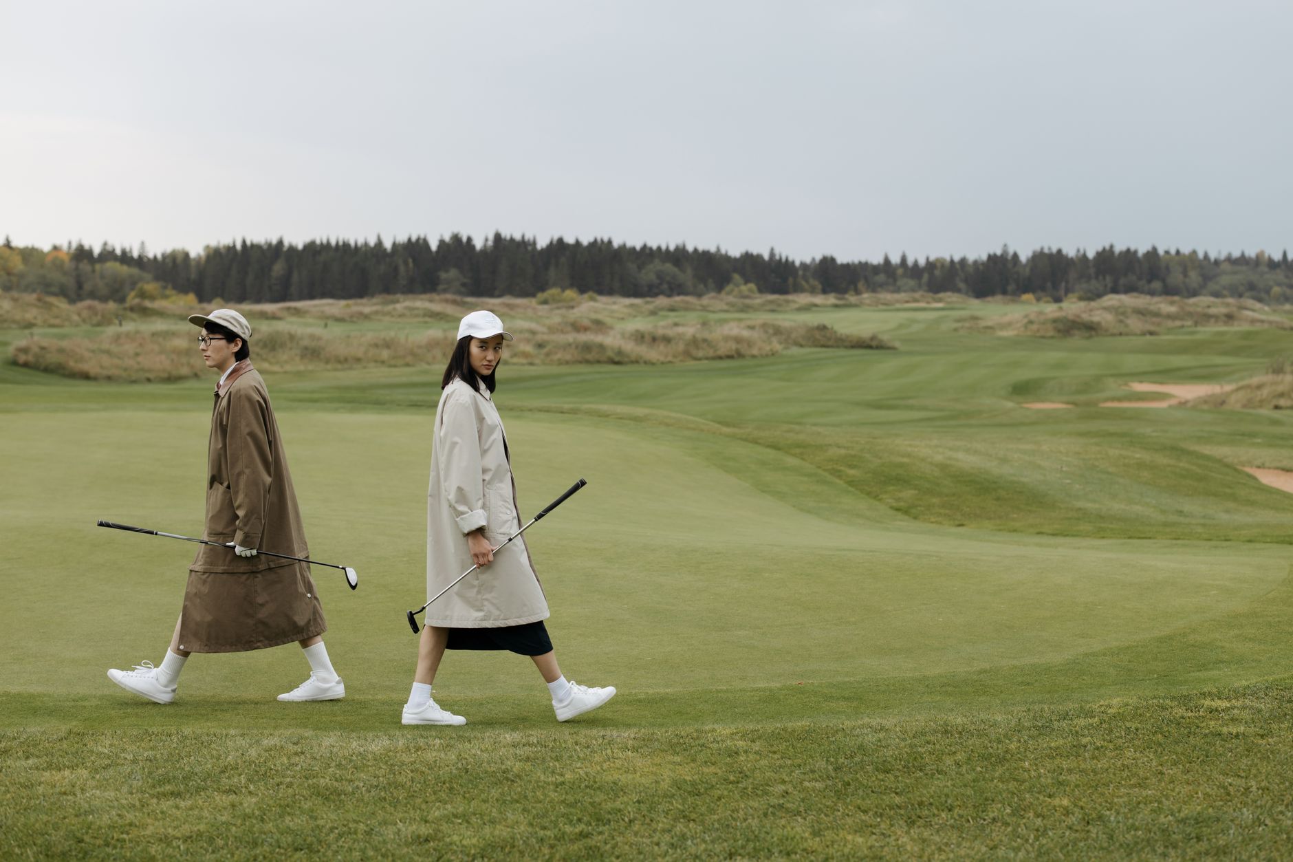 Two golfers walking together across an open golf course.