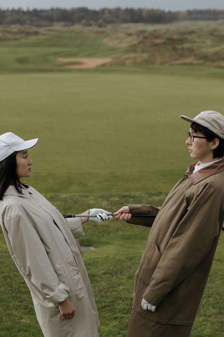 Man And Woman In Coats Posing In Golf Course