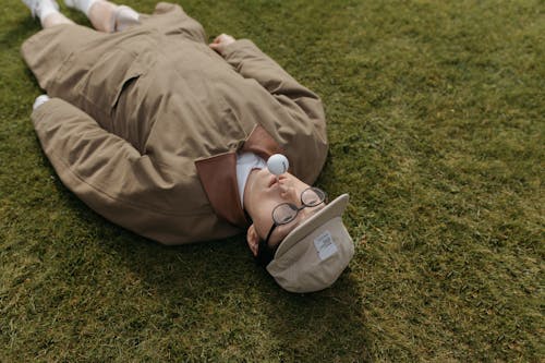Man in Brown Dress Shirt Lying on Green Grass Field