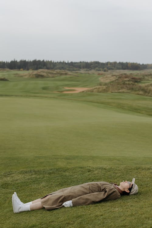 Person Lying on Green Grass of a Golf Course