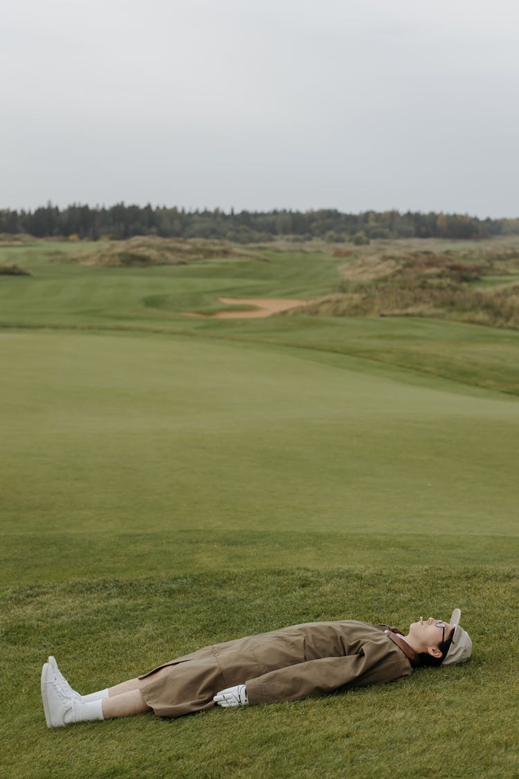 Person Lying On Green Grass Of A Golf Course