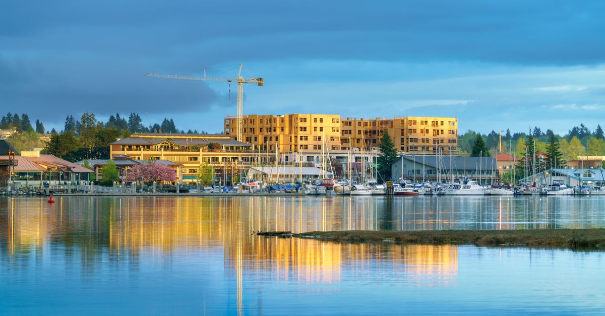 Scenic waterfront view of boats, buildings, and construction crane at sunset.