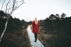 A woman in a red coat walks on a forest boardwalk in Ohlstadt, Germany.