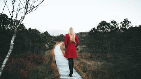 A woman in a red coat walks on a forest boardwalk in Ohlstadt, Germany.