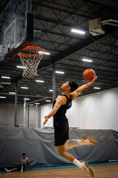 Athlete executing an impressive dunk during a basketball game on an indoor court.
