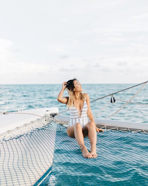 A woman enjoys a peaceful moment on a yacht's net, surrounded by the ocean's calm blue waters.