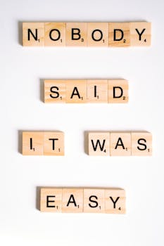 Scrabble tiles spelling 'Nobody said it was easy' on a white surface.