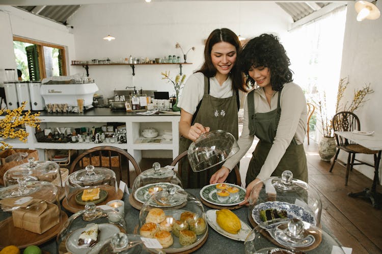 Happy Women Serving Desserts In Cafe