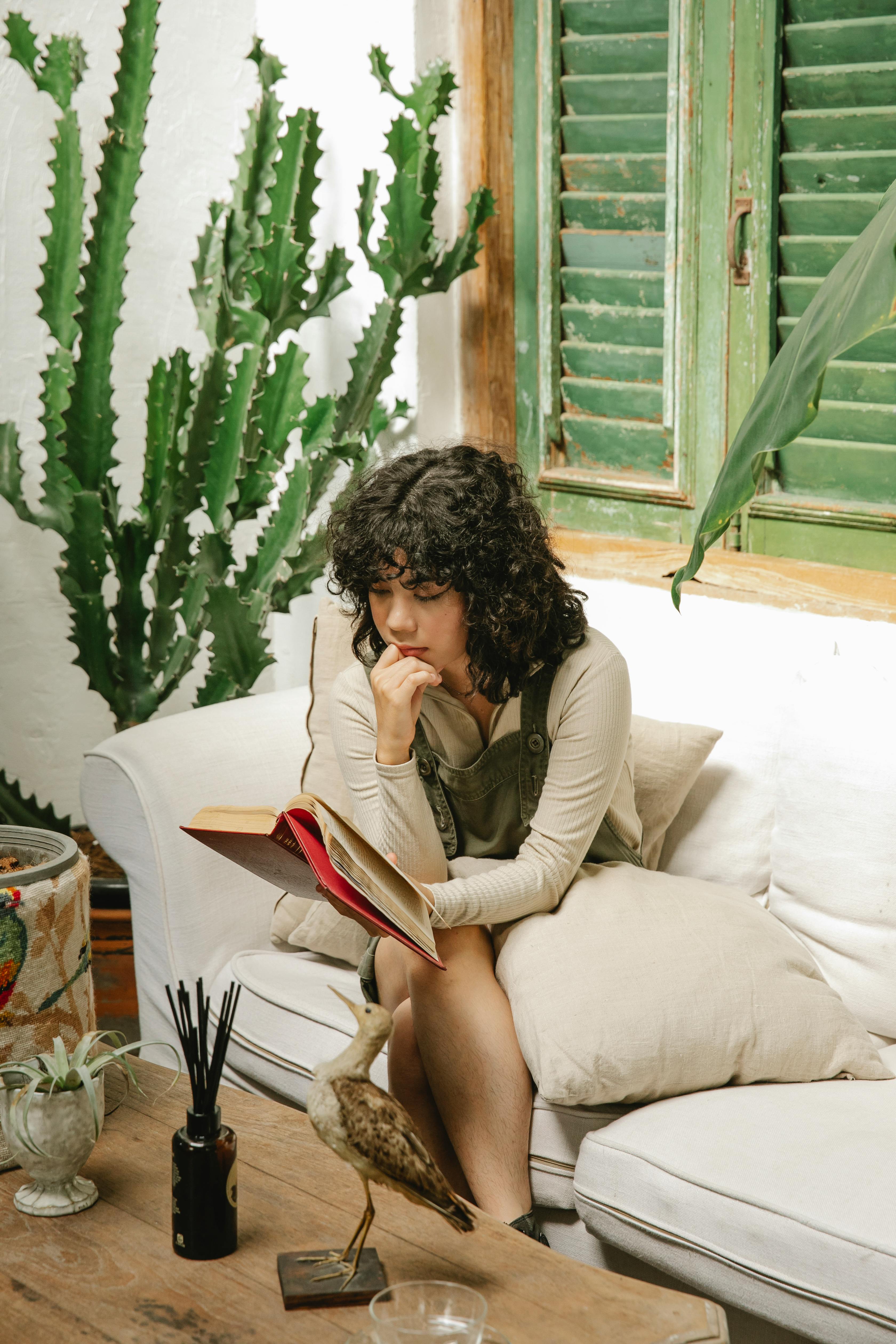 concentrated female reading book in living room with plants