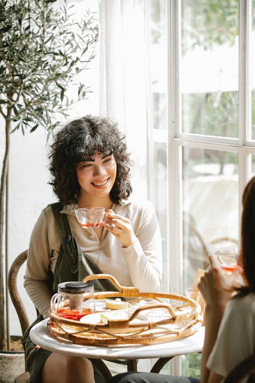 Free Smiling ethnic woman having breakfast with friend Stock Photo