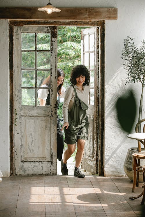 Smiling diverse friends walking into doorway of rustic house