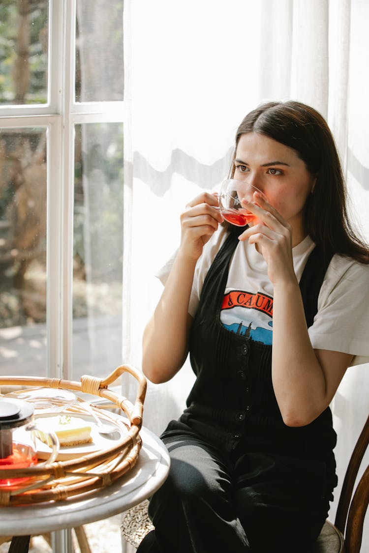 Young Woman Drinking Brewed Tea From Glass Cup