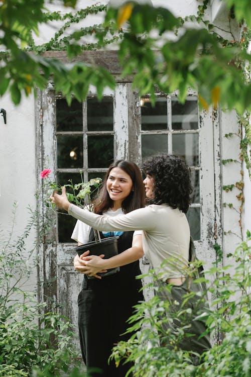 Positive women standing near entrance of building with potted plant