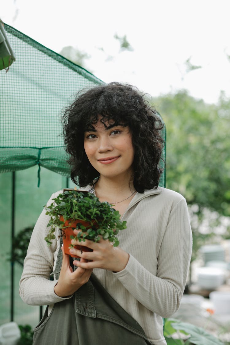 Smiling Ethnic Gardener With Seedling In Pot