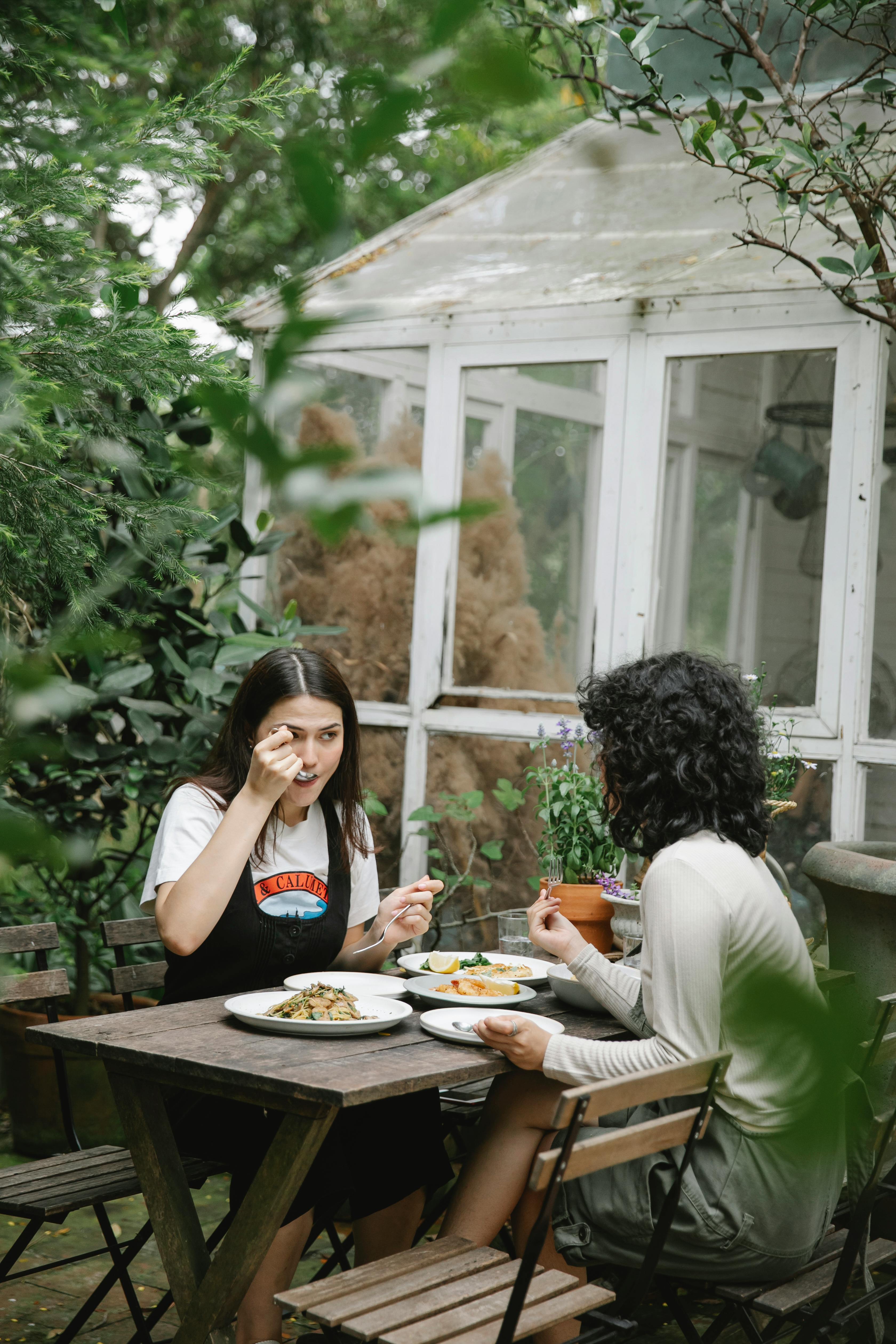 female gardeners eating lunch at table in backyard