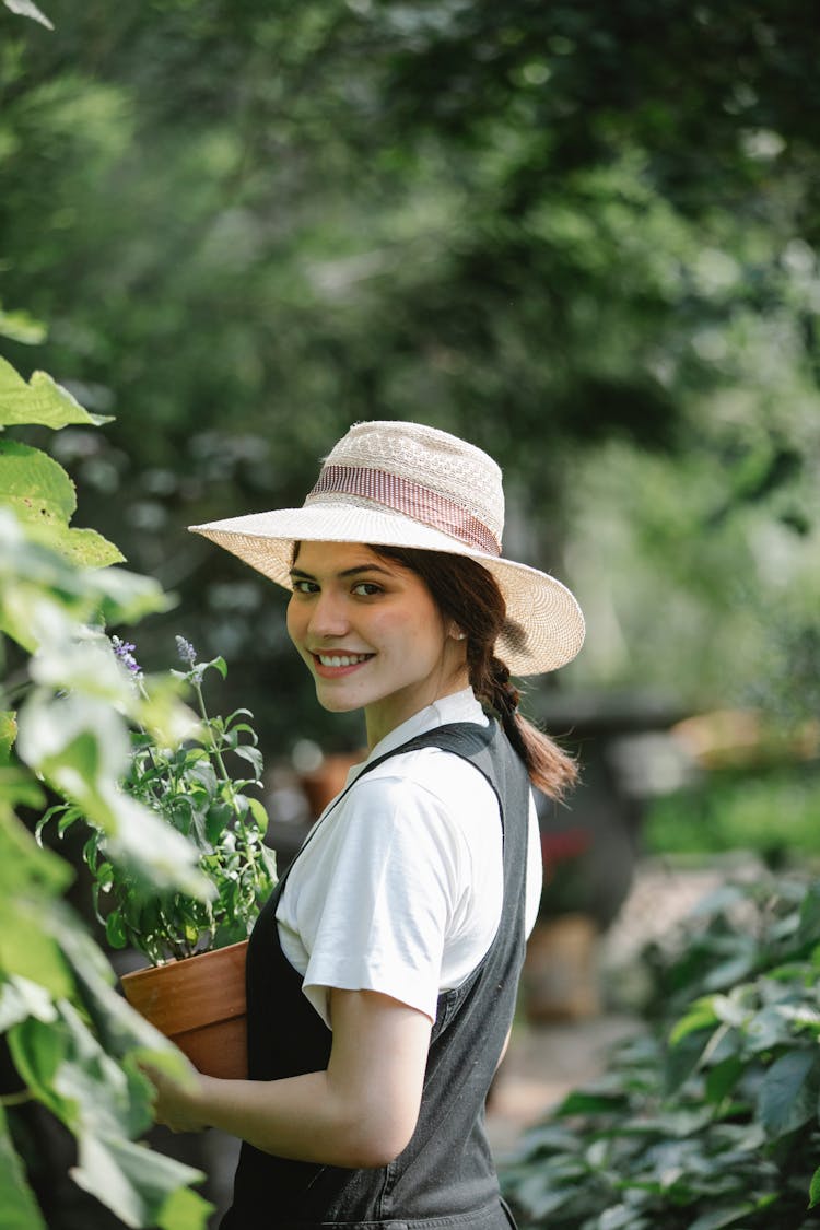 Smiling Gardener With Potted Plant In Backyard