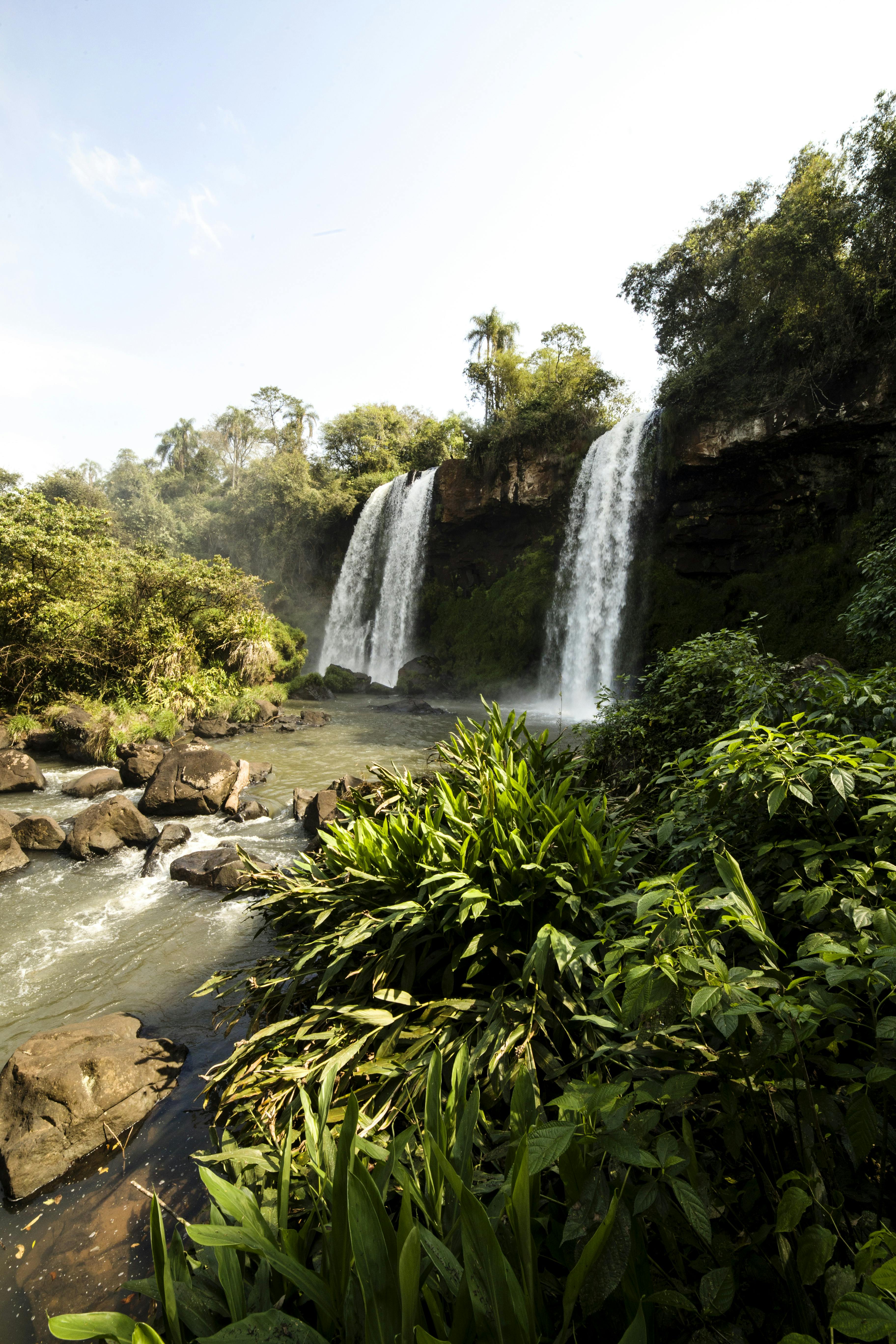 powerful waterfalls in green jungle against blue sky