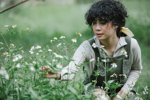 緑の芝生のフィールドに座っている白いカーディガンの女性