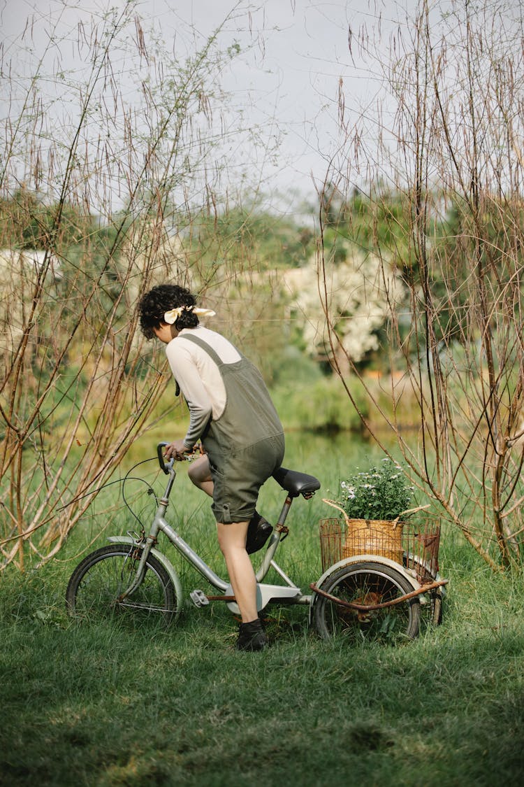 Woman Taking Seat On Bike On Lake Coast