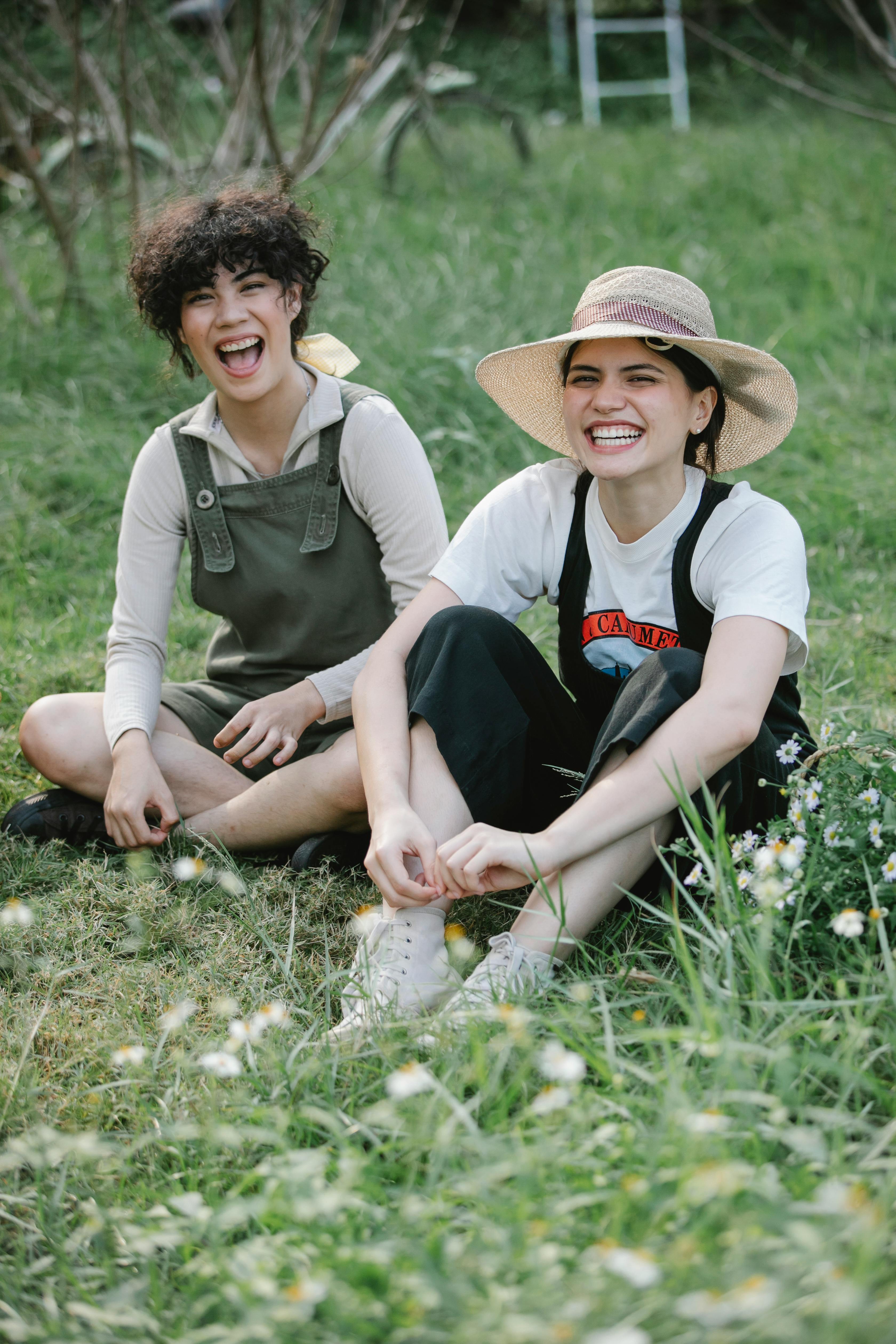 happy multiethnic female friends sitting on green field in countryside