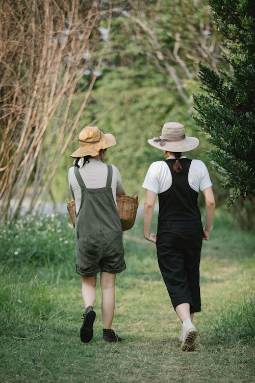 푸른 잔디 필드에 걷는 갈색 밀짚 모자와 흰 셔츠와 검은 치마 여자