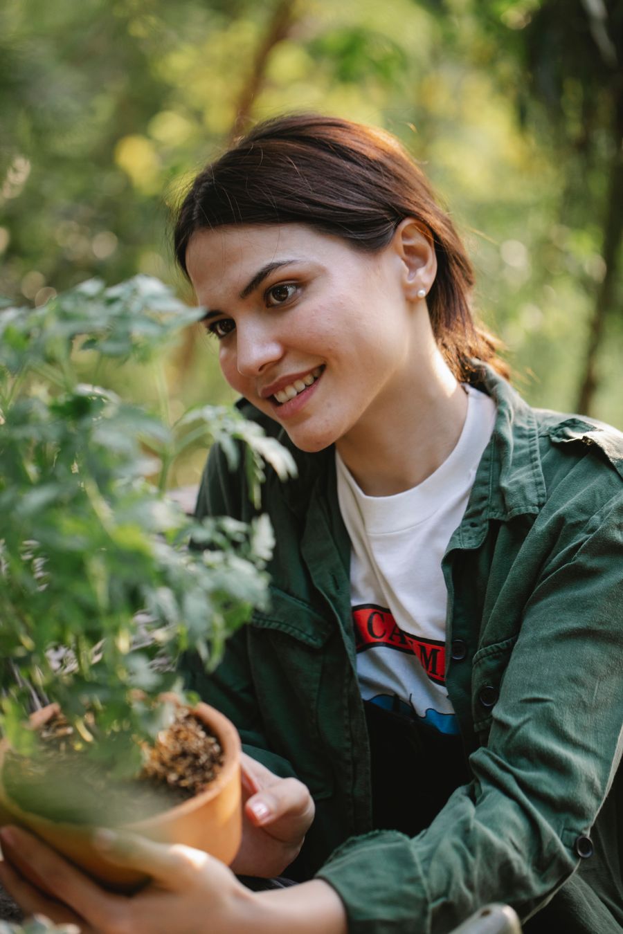 A smiling Thistle and Thrive gardener kneeling with gardening tools