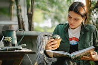 Gardener with plant reading book in armchair