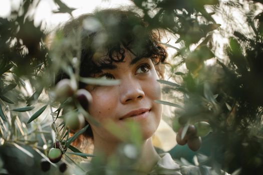 Dreamy ethnic gardener among olive branches in countryside