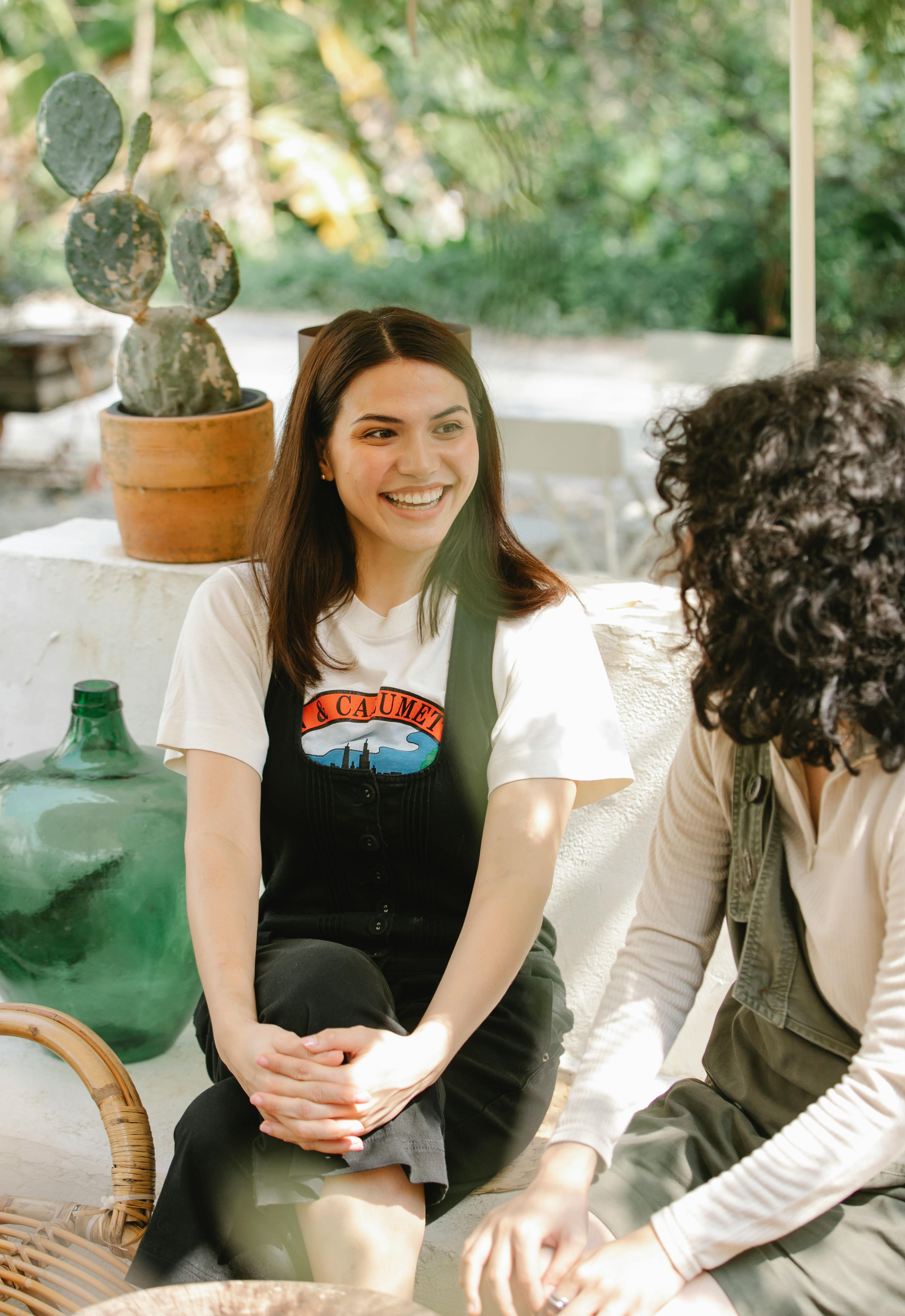 cheerful ethnic coworkers chatting on couch in garden