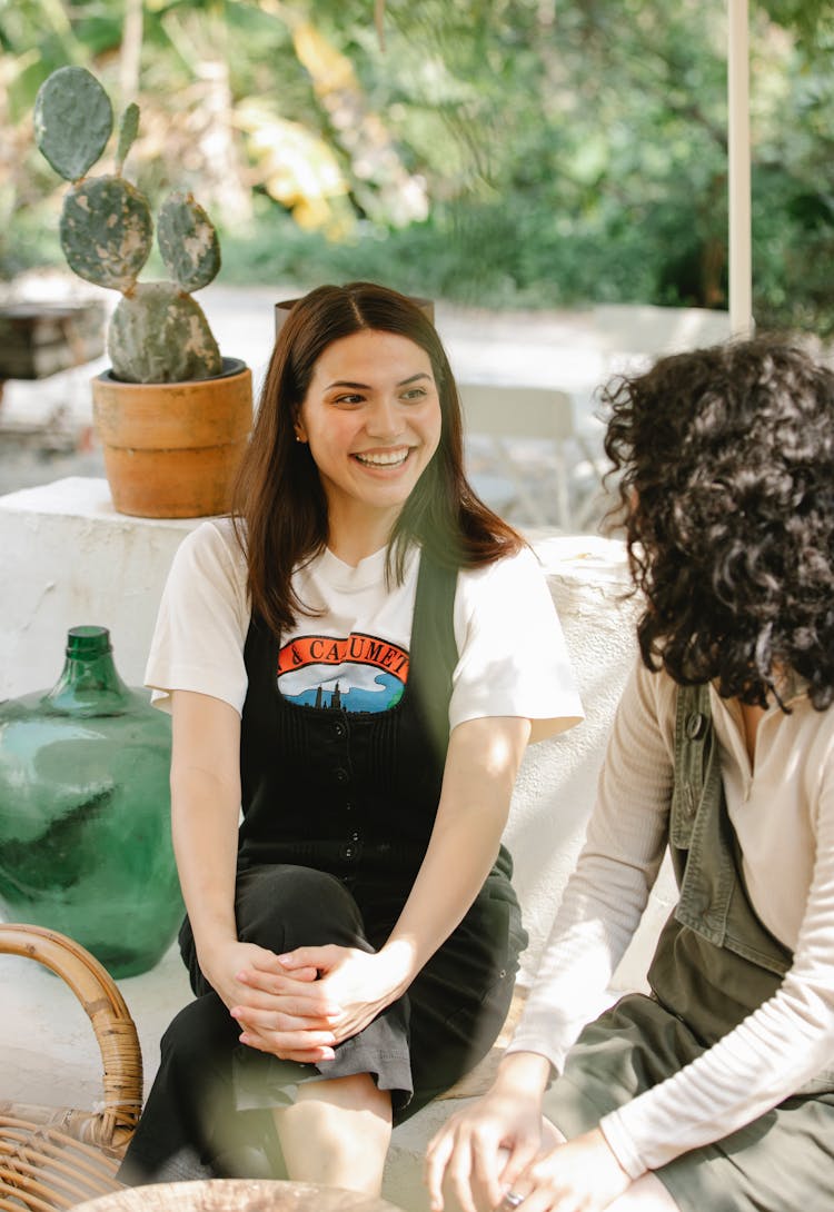 Cheerful Ethnic Coworkers Chatting On Couch In Garden