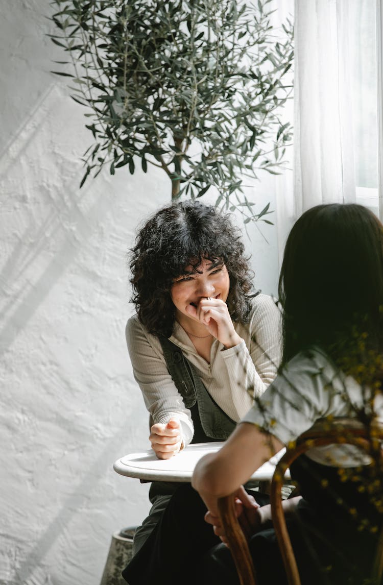 Positive Ethnic Female Coworkers At Table In Cafe