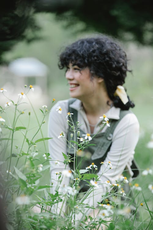 Smiling ethnic woman sitting near flowers