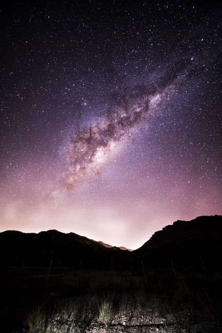 From below of breathtaking scenery of purple starry night sky and Milky Way galaxy over mountainous valley